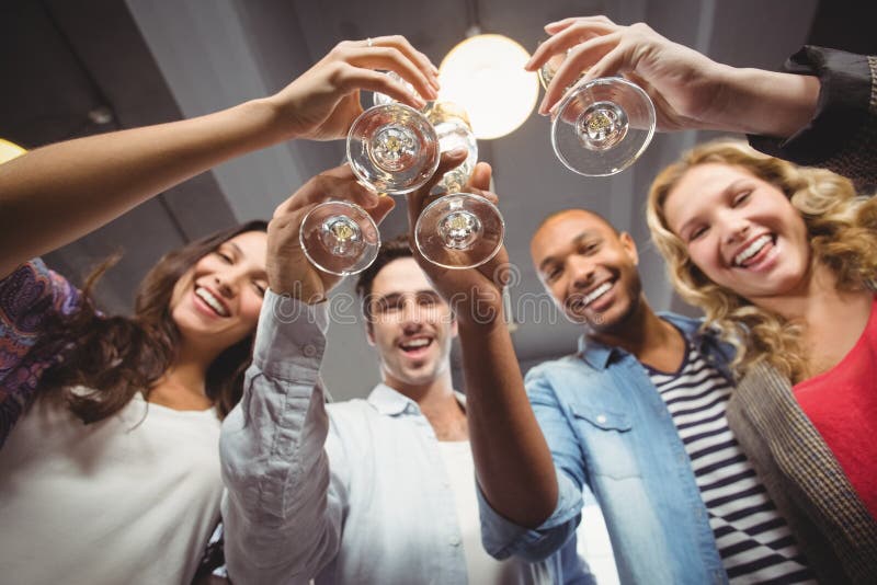 Low angle portrait of cheerful colleagues toasting in office stock photo Low angle portrait of cheerful colleagues toasting in office stock photo