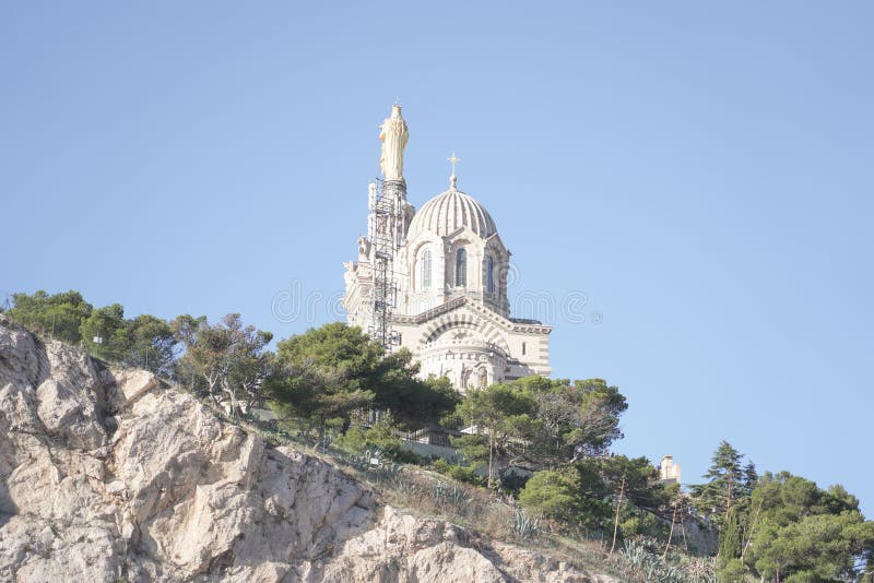 Low-angle shot the cathedral of Notre dame de lagarde in Marseille, France atop a rocky outcrop