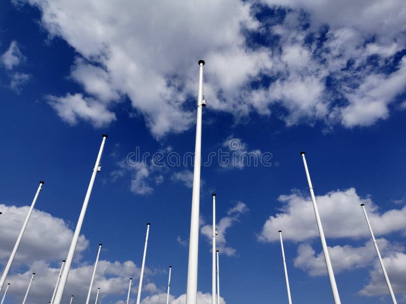 Low Angle Shot of Tall White Poles in a Cloudy Blue Sky Stock Photo
