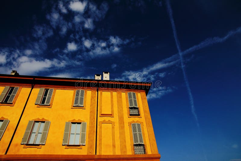 Low Angle Shot Of A Yellow House With Windows Under The Blue Sky