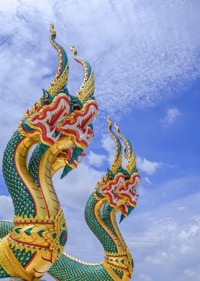 Low angle and side view of 2 colorful 3-headed serpent statues against white clouds on blue sky background royalty free stock photo