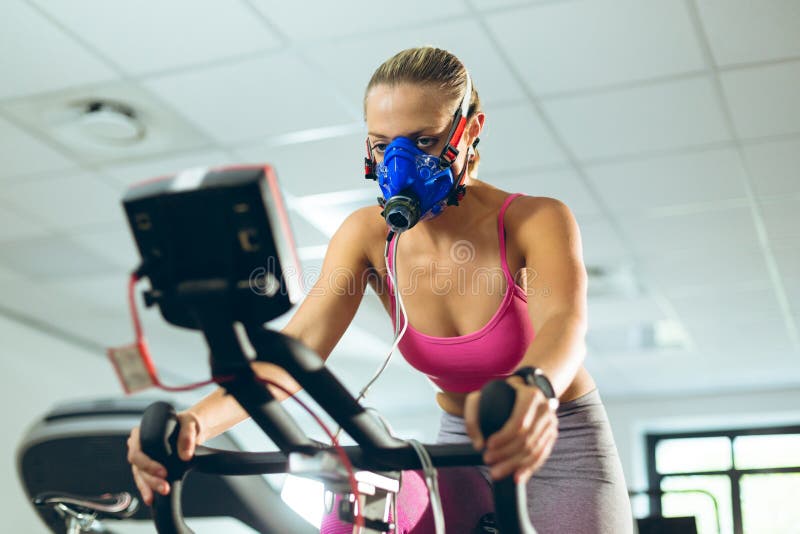Female Athlete with Mask Exercising with Exercise Bike in Fitness Studio Stock Image - Image of active, hair: 154104721