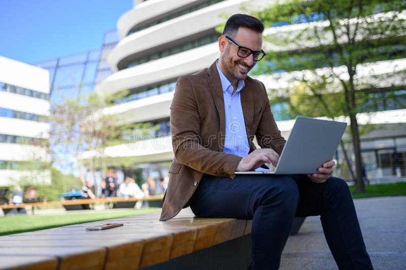Vedere cu unghi redus a mesajelor de e-mail profesionale de citire focalizate pe notebook în timp ce stau pe bancă în oraș stock images
