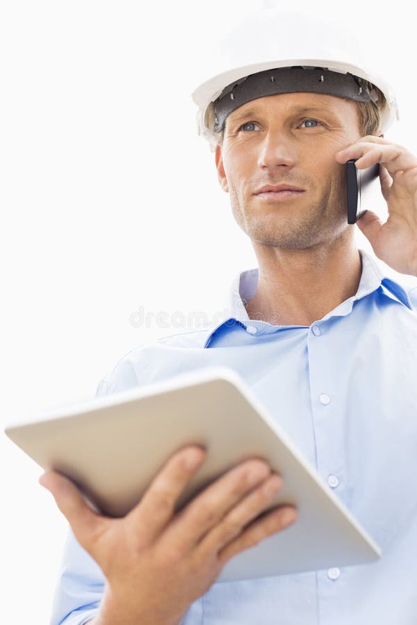 Low angle view of male architect with digital tablet using cell phone against sky