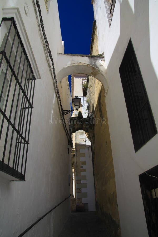 Low angle view on narrow empty alley with facades of white houses and steps upstairs contrasting with dark blue sky in traditional royalty free stock photo Low angle view on narrow empty alley with facades of white houses and steps upstairs contrasting with dark blue sky in traditional royalty free stock photo