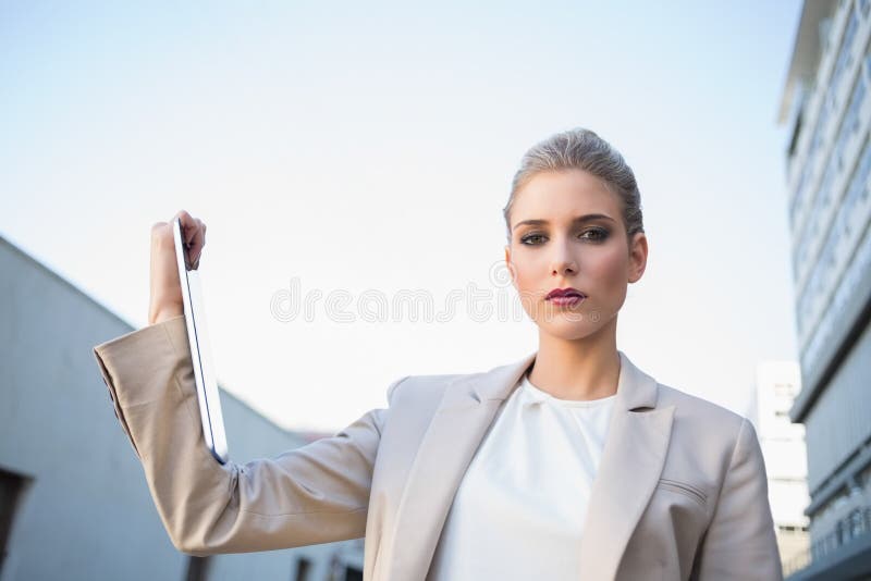 Low angle view of serious classy businesswoman holding tablet