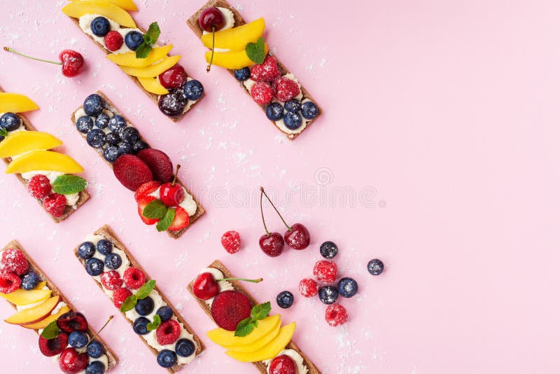 Low calorie snack or dessert from sandwiches with creamy cheese and summer berry fruits on pink trendy background top view.