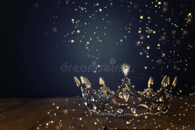 low key image of beautiful queen/king crown over wooden table. vintage filtered. fantasy medieval period. Glitter sparkle lights