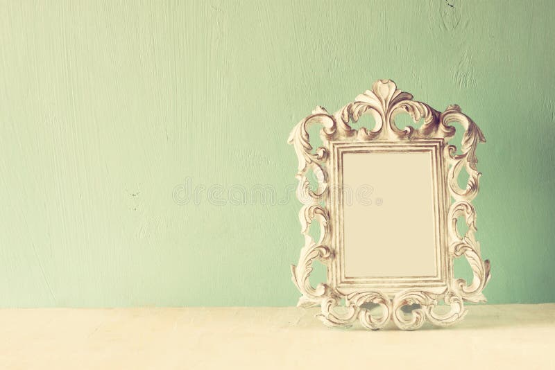 Low key image of vintage antique classical frame on wooden table. filtered image.