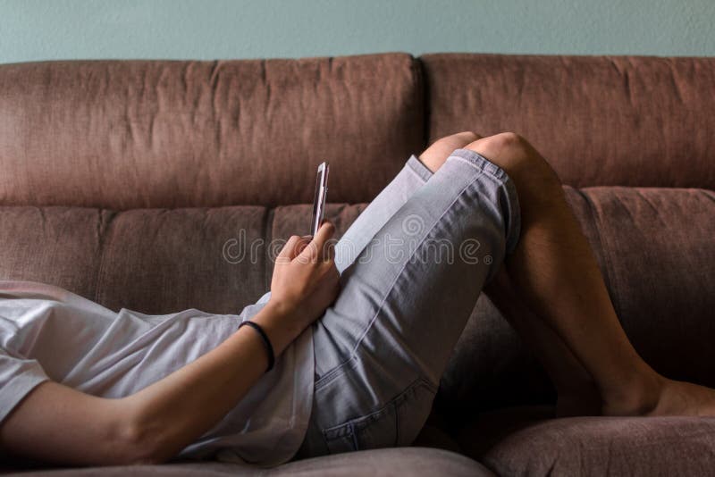 Low section of man using mobile phone while lying on sofa at home royalty free stock images Low section of man using mobile phone while lying on sofa at home royalty free stock images