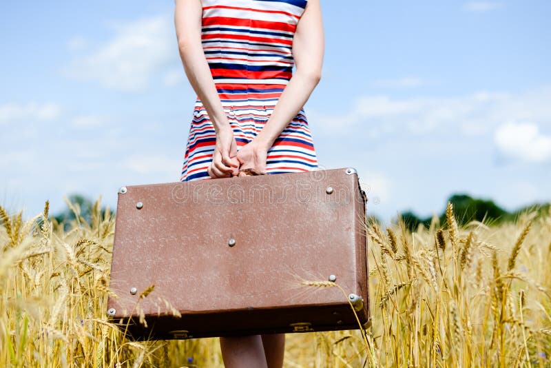Lower half of woman holding old suitcase over stock photo Lower half of woman holding old suitcase over stock photo