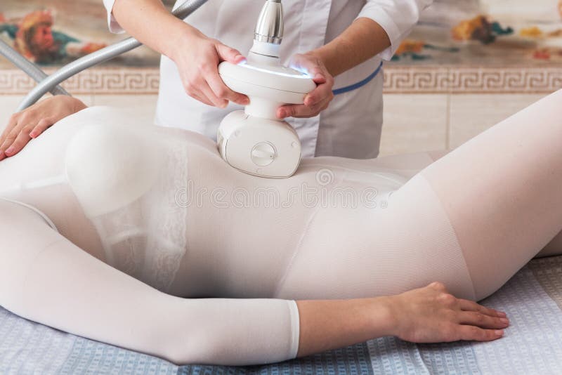 Woman in special white suit getting anti cellulite massage in a spa salon. LPG, and body contouring treatment in clinic. Lipomassage procedure on female body. Woman in special white suit getting anti cellulite massage in a spa salon. LPG, and body contouring treatment in clinic. Lipomassage procedure on female body.