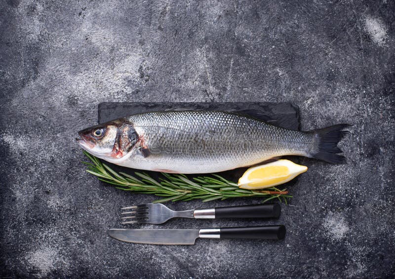 Lubina de los pescados crudos con el limón y el romero fotografía de archivo Lubina de los pescados crudos con el limón y el romero fotografía de archivo