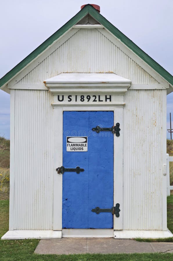 The Oil House at the Lighthouse at Dungeness Spit near Sequim Washington state. Fuel oil used by the lighthouse in stored here. Rusty blue door. Sign says Flammable Liquids. The Oil House at the Lighthouse at Dungeness Spit near Sequim Washington state. Fuel oil used by the lighthouse in stored here. Rusty blue door. Sign says Flammable Liquids.