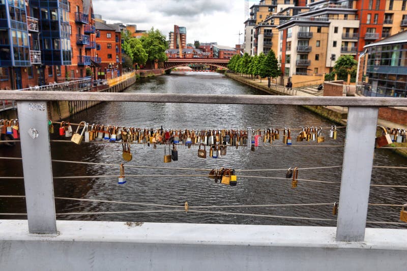 LEEDS, UK - JULY 12, 2016: Love padlocks on a foot bridge crossing River Aire in The Calls, former industrial area in Leeds. Now it`s redeveloped with restaurants and apartment buildings. LEEDS, UK - JULY 12, 2016: Love padlocks on a foot bridge crossing River Aire in The Calls, former industrial area in Leeds. Now it`s redeveloped with restaurants and apartment buildings