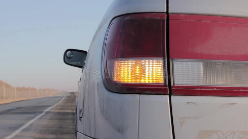 Luce arancio infiammante del lampeggiatore sul faro posteriore automobile sull'attività collaterali