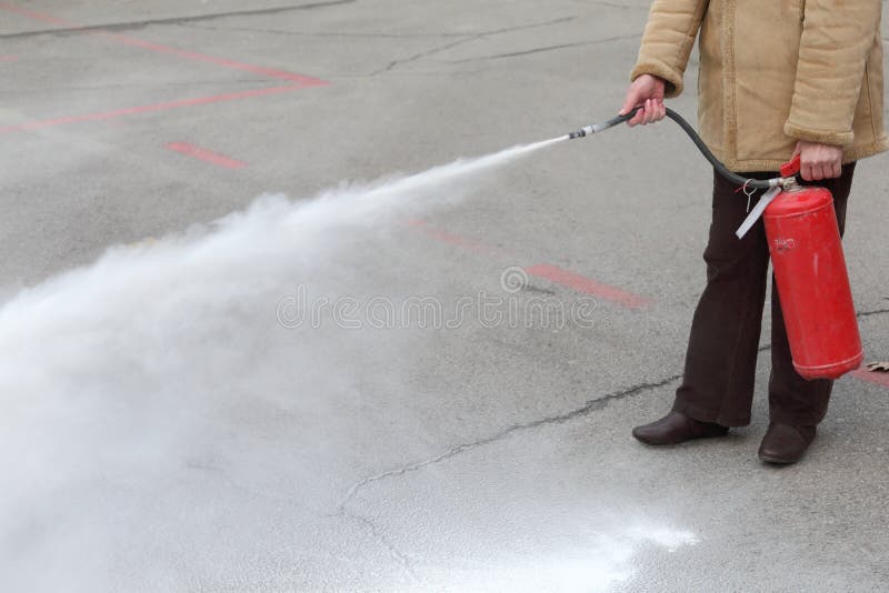 A woman demonstrating how to use a fire extinguisher. A woman demonstrating how to use a fire extinguisher