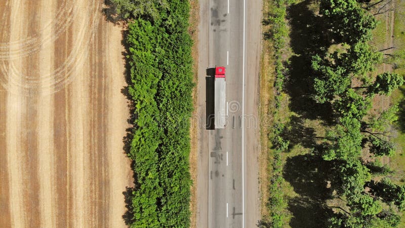 lucht Rode vrachtwagen op een weg tussen gebieden De achtergrond van de vervoerlogistiek royalty-vrije stock afbeelding lucht Rode vrachtwagen op een weg tussen gebieden De achtergrond van de vervoerlogistiek royalty-vrije stock afbeelding