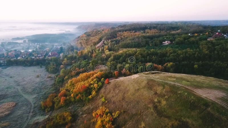 Lucht Videolengte De mooie aard van het de herfstplatteland Heuvel met weg op bovenkant en dorp op achtergrond