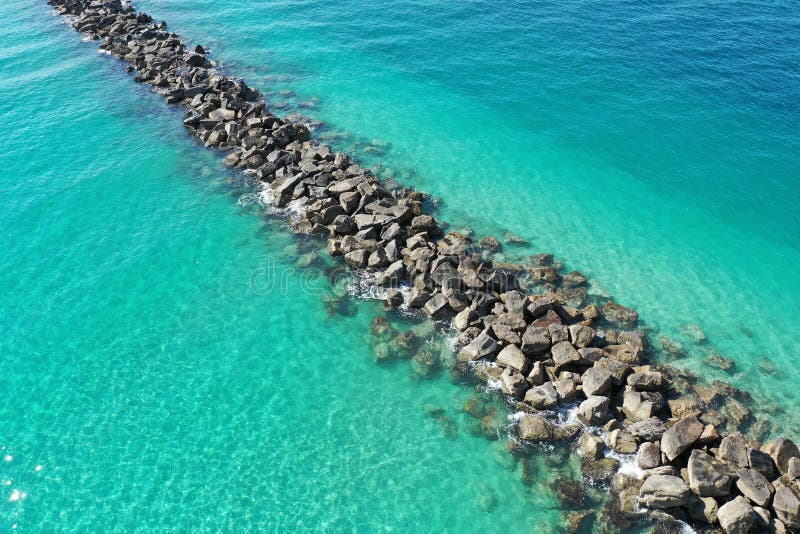 Aerial view of rock jetty of Government Cut surrounded by clear shallow water of Miami Beach, Florida on sunny summer morning. Aerial view of rock jetty of Government Cut surrounded by clear shallow water of Miami Beach, Florida on sunny summer morning.