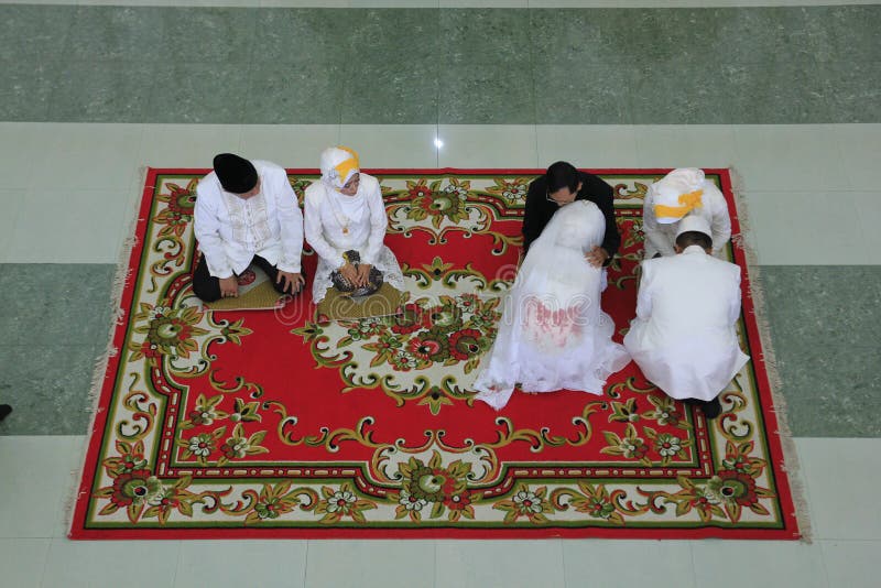 Luchtfoto van een paar moslimbriden die hun hoofd buigen en vragen om gebeden voor hun ouders in de Javanese traditie royalty-vrije stock foto's Luchtfoto van een paar moslimbriden die hun hoofd buigen en vragen om gebeden voor hun ouders in de Javanese traditie royalty-vrije stock foto's