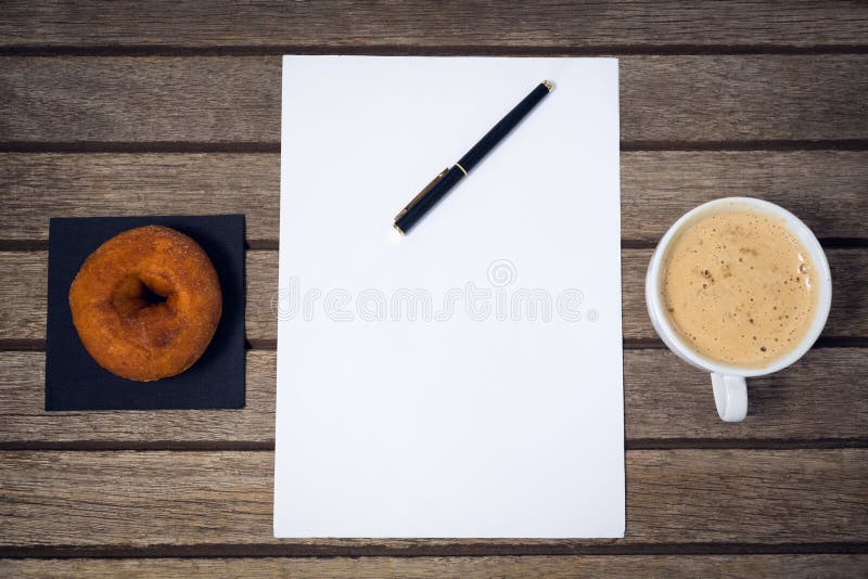 Luchtmening van koffiekop met vulpen op papier door doughnut stock foto's Luchtmening van koffiekop met vulpen op papier door doughnut stock foto's