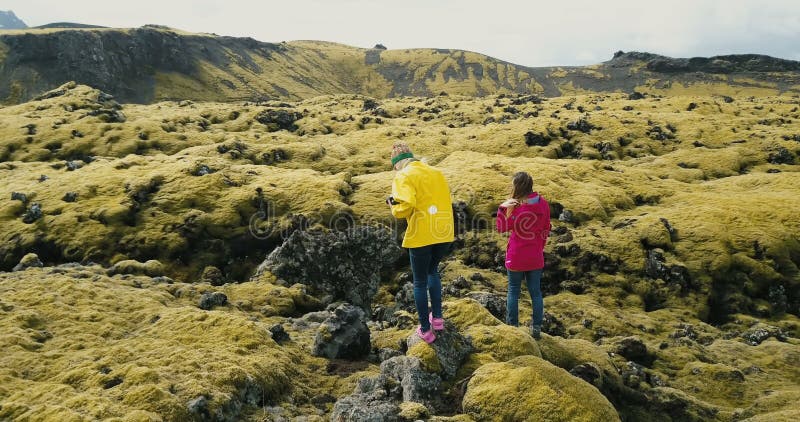 Luchtmening van twee vrouw het lopen op het lavagebied in IJsland Toeristen die het weide behandelde mos, wandeling onderzoeken