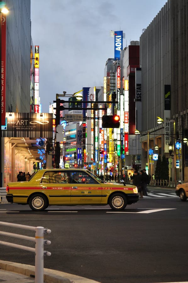 Neon lights on storefronts of Shinjuku in Tokyo, Japan with a taxi driving pass. Neon lights on storefronts of Shinjuku in Tokyo, Japan with a taxi driving pass.