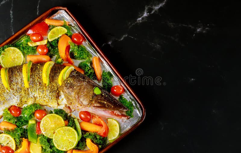 Lucio de pescado sin cocer con cal y verdura en una sartén imagen de archivo libre de regalías