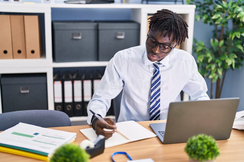 Lucrător din America Africană care utilizează un notebook scris pe notebook la birou stock photo