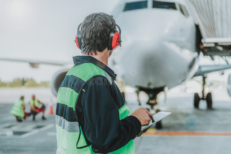 Lucrător în căști roșii privind un avion uriaș royalty free stock photos