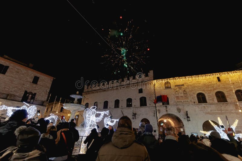 Assisi, Italy - January 1, 2024: people partying in the main square of the city for New Year's Eve at night with fireworks and a concert. Assisi, Italy - January 1, 2024: people partying in the main square of the city for New Year's Eve at night with fireworks and a concert