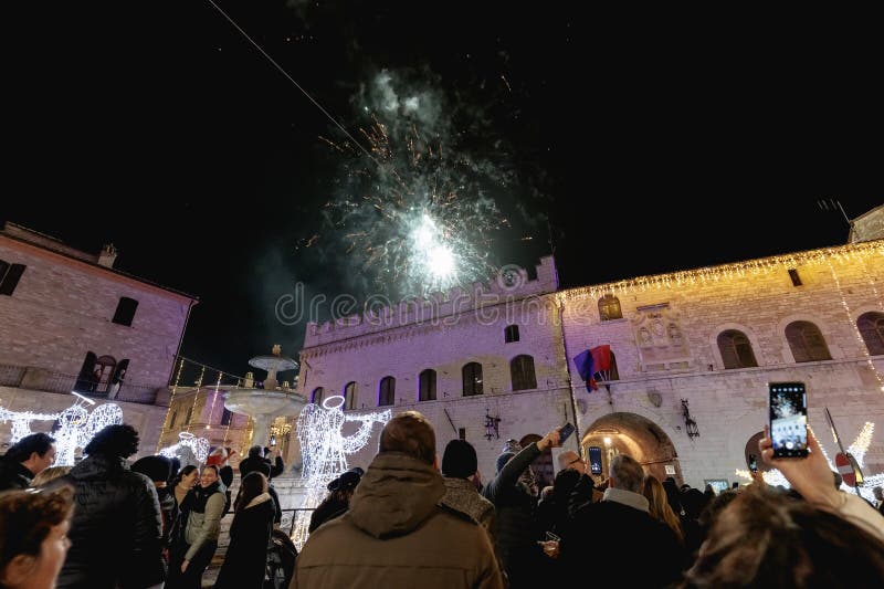 Assisi, Italy - January 1, 2024: people partying in the main square of the city for New Year's Eve at night with fireworks and a concert. Assisi, Italy - January 1, 2024: people partying in the main square of the city for New Year's Eve at night with fireworks and a concert