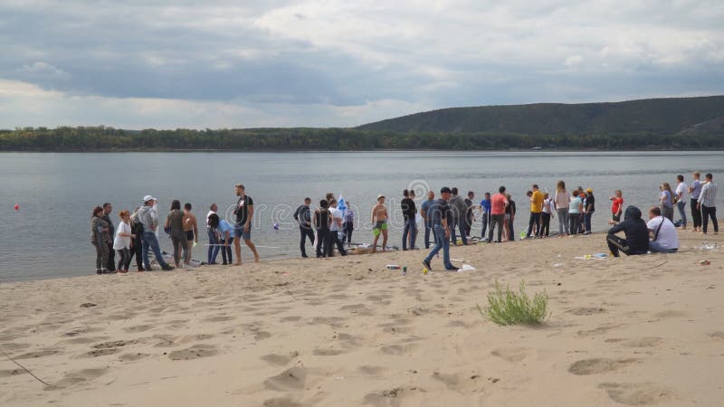 Ludzie stoją i chodzą po piaszczystej plaży na brzegu rzeki