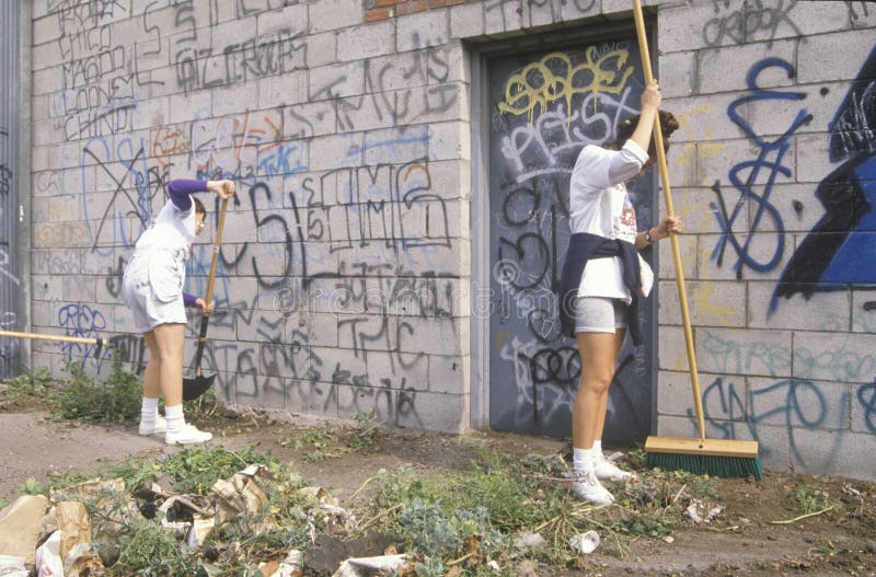 A group of young people participating in community cleanup by sweeping an alley. A group of young people participating in community cleanup by sweeping an alley