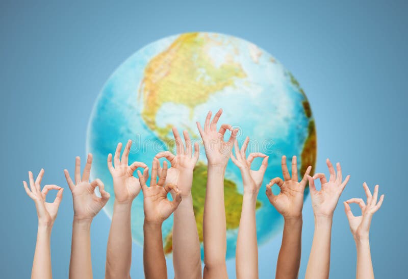Gesture, people, humanity and community concept - human hands showing ok sign over earth globe and blue background. Gesture, people, humanity and community concept - human hands showing ok sign over earth globe and blue background