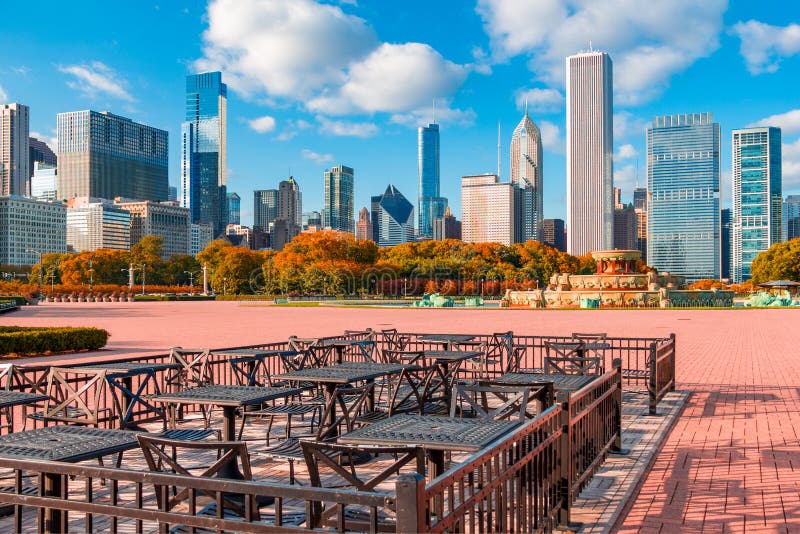 Tables and chairs in the Grant Park bricked area sit in front of fall colored trees and an  extensive panorama of the skyline of Chicago. Tables and chairs in the Grant Park bricked area sit in front of fall colored trees and an  extensive panorama of the skyline of Chicago.