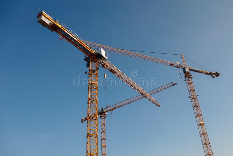 Luffing jib tower crane at large scale construction site with blue sky