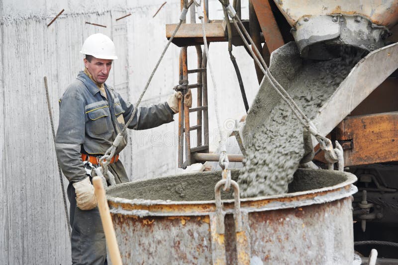 Builder worker pouring concrete from automobile mixer into construction barrel. Builder worker pouring concrete from automobile mixer into construction barrel