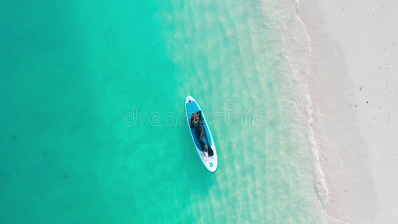 Luftbild einer Frau auf einem Surfbrett im türkisfarbenen Wasser der Malediven. stock video footage