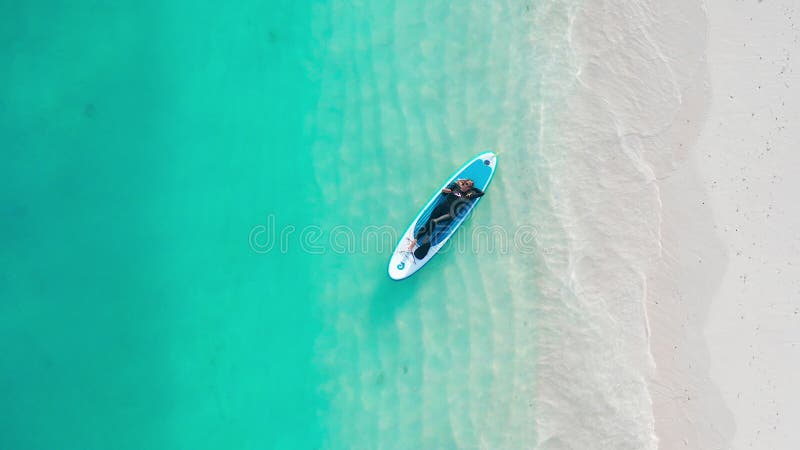 Luftbild einer Frau auf einem Surfbrett im türkisfarbenen Wasser der Malediven. stock video