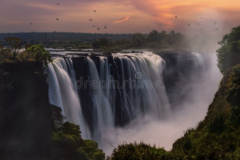 Luftbild Mosioatunya Wasserfall in Sambia bei Sonnenuntergang mit Vögeln herumfliegen