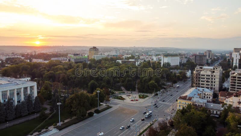 Aerial drone panorama view of Chisinau downtown at sunset, central street with govermental buildings, moving cars, central park with green trees. Aerial drone panorama view of Chisinau downtown at sunset, central street with govermental buildings, moving cars, central park with green trees