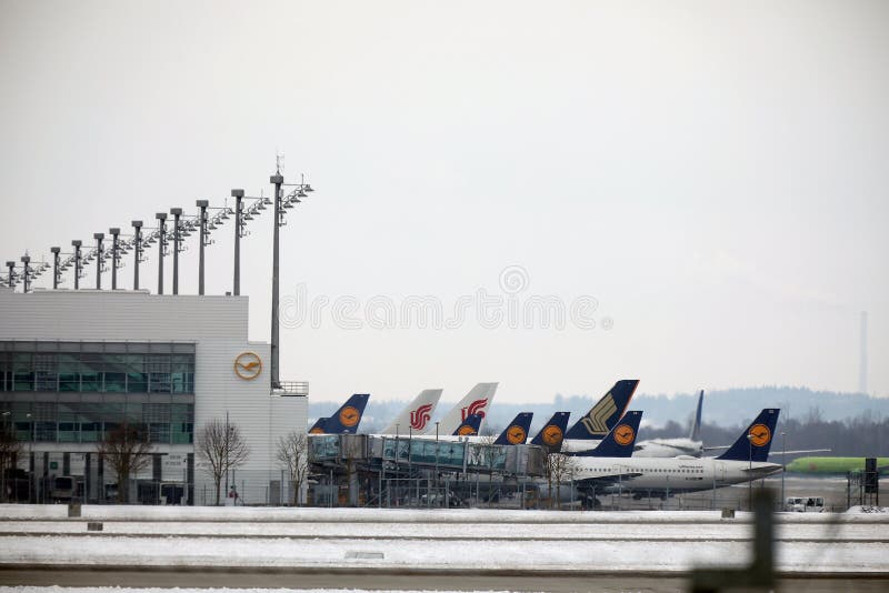Lufthansa hyvlar på slutliga portar, den Munich flygplatsen, vintertid med snö royaltyfri bild Lufthansa hyvlar på slutliga portar, den Munich flygplatsen, vintertid med snö royaltyfri bild