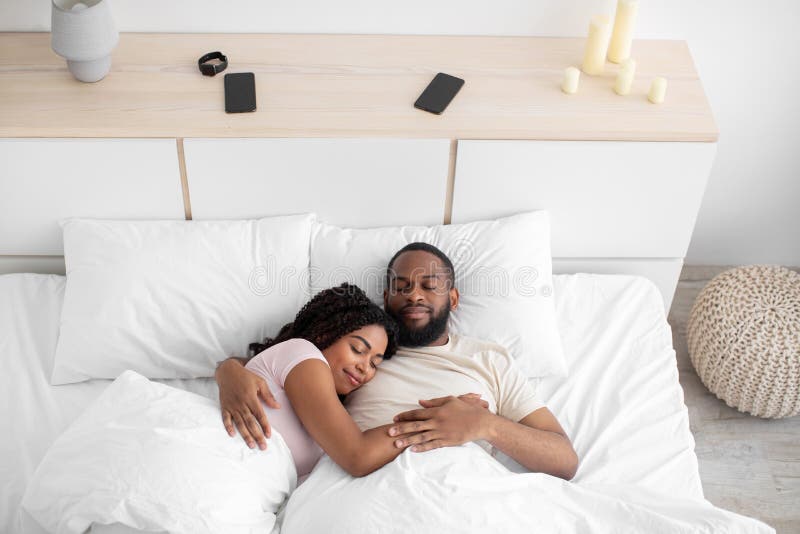 Lugn tusal afrikansk amerikan kvinna och man sover på nattkrämning i sovrummets insida. Lugn tusal afrikansk amerikan kvinna och man sover på nattkrämning på sängen i sovrumsfritt utrymme.. relaxering och friska sömn tillsammans under helgen, kärlek och relationer, toppvy