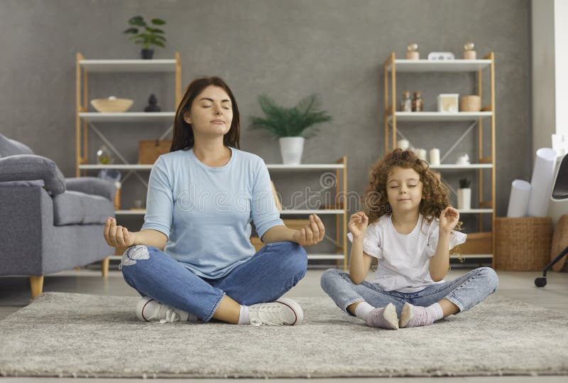 Lugn, ung mor och dotter tränar yoga hemma arkivbilder