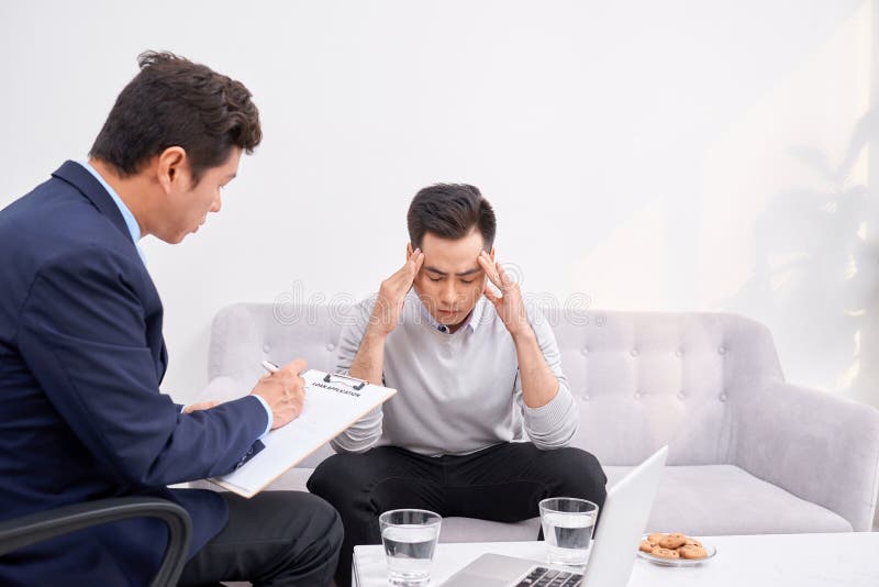 Luister aan me Aziatische mens die voorhoofd rimpelen terwijl het bekijken zijn therapeut stock foto Luister aan me Aziatische mens die voorhoofd rimpelen terwijl het bekijken zijn therapeut stock foto