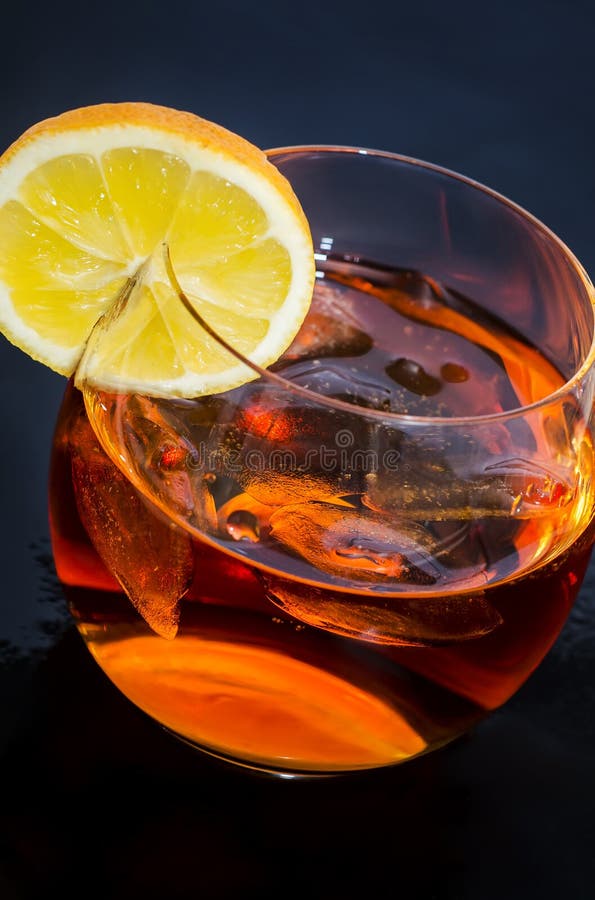 Glass of iced alcohol drink with lemon. Over dark blue background. Glass of iced alcohol drink with lemon. Over dark blue background.