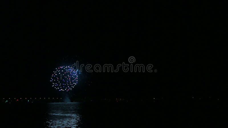 Luminosos fuegos artificiales festivos en el cielo nocturno sobre el río con reflejo en el agua