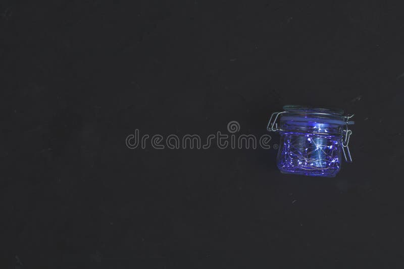 Lumière bleue de Noël en pot de verre sur fond de béton noir Espace de copie, vue supérieure photos libres de droits Lumière bleue de Noël en pot de verre sur fond de béton noir Espace de copie, vue supérieure photos libres de droits